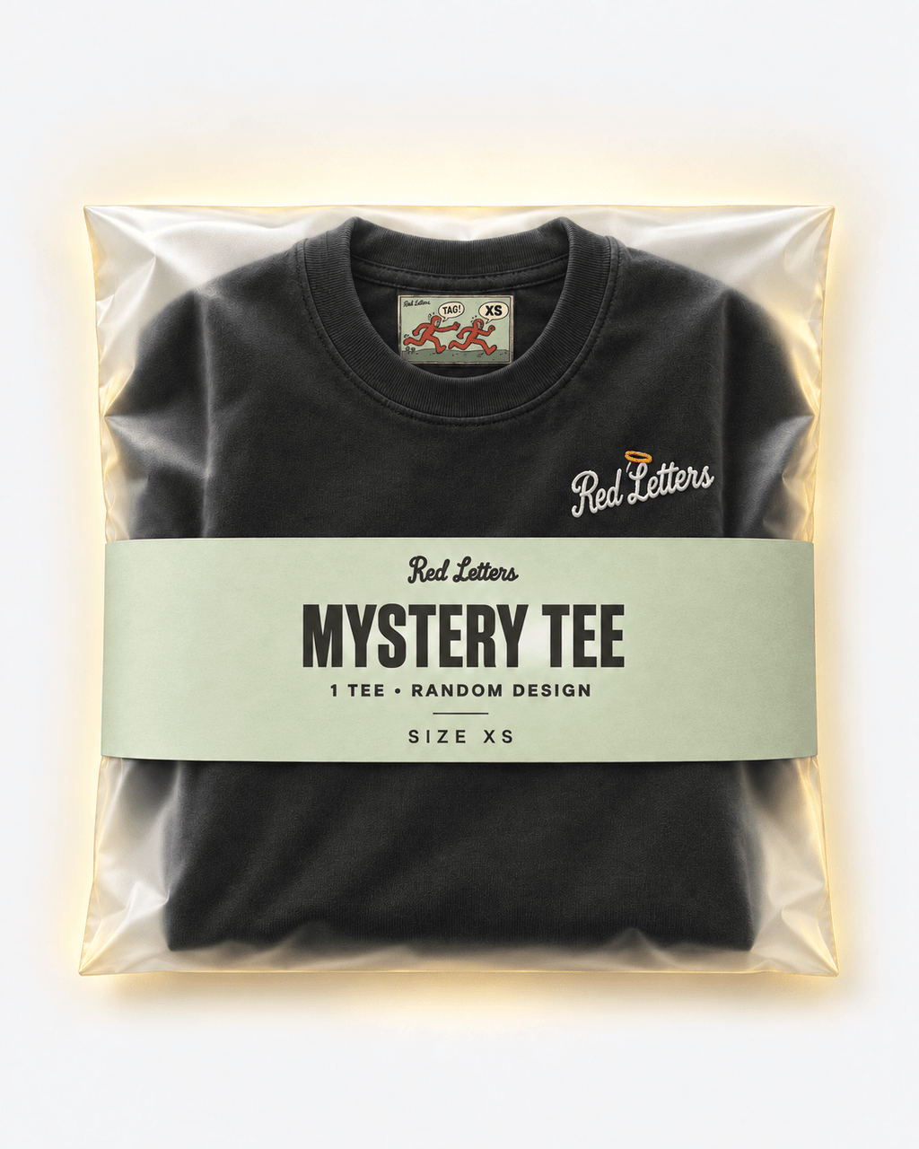 Red Letters Mystery Tee, size XS, with a stitched illustrated neck tag, subtle embroidered chest logo and pistachio packaging. One tee, random design.