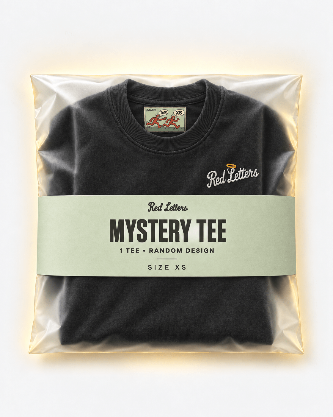 Red Letters Mystery Tee, size XS, with a stitched illustrated neck tag, subtle embroidered chest logo and pistachio packaging. One tee, random design.